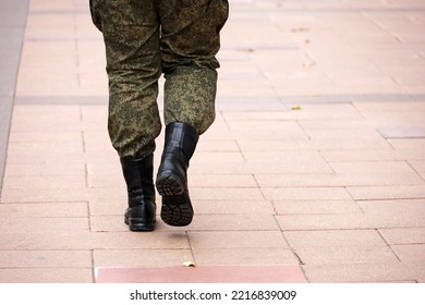 Soldier In Military Camouflage And Boots Walking Down The City Street, Legs On Sidewalk. Concept Of Service In Army, Mobilization