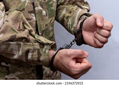 A soldier in a military camouflage uniform is handcuffed on a light background. Concept: a military tribunal over a criminal, an army court. - Powered by Shutterstock