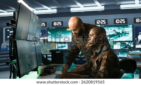 Soldier in military HQ base doing brainstorming with coworker, gathering information on enemy troops. Teamworking officers using tracking software to do assessment of enemy vulnerabilities, camera B
