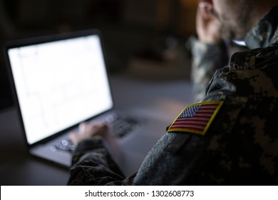 Soldier In Military Uniform Typing On A Computer. Focus On USA Flag.