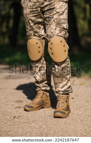 Soldier in protective uniform. Protective camouflage uniform. Elbow pads and knee pads for soldiers