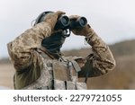 soldier, ranger or hunter with binoculars watching the forest