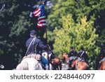 A soldier riding a horse and raises the flag of America during military performance in the Civil war reenactment in Jackson city, Michigan, USA