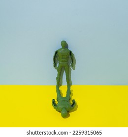 A soldier is standing and one is lying with his face turned to the ground. Conceptual setting of war and suffering. Two-tone background. - Powered by Shutterstock