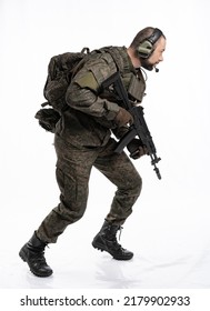 Soldier In The Studio On A White Background. A Man In Military Uniform With A Rifle Or Machine Gun. Military Or Airball Player