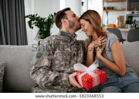 Soldier surprising his wife with a gift. Young man giving gift box to his girlfriend.	


