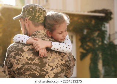 Soldier in Ukrainian military uniform hugging his daughter outdoors, space for text. Family reunion - Powered by Shutterstock