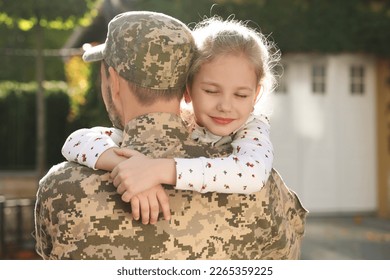 Soldier in Ukrainian military uniform hugging his daughter outdoors. Family reunion - Powered by Shutterstock