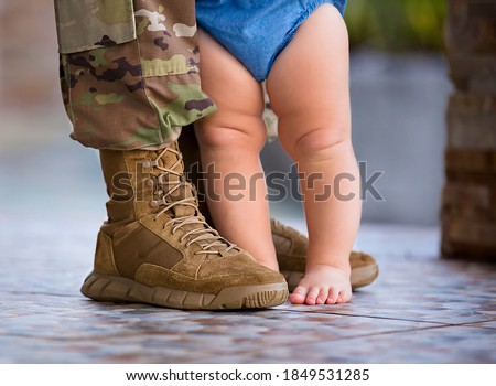 Soldier in uniform and baby at his feet