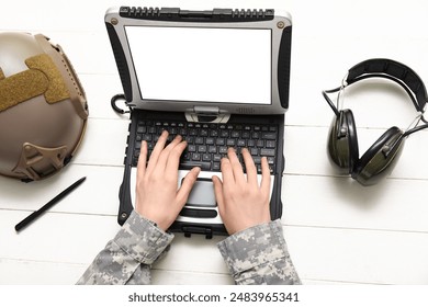 Soldier in uniform with military laptop, headphone and helmet on white wooden table - Powered by Shutterstock