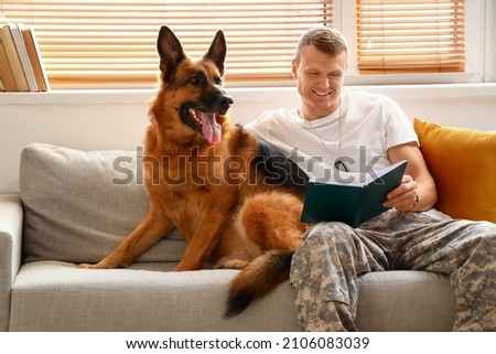 Soldier of USA army with military working dog reading book at home