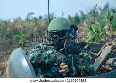 Soldier Using Communication Device, A soldier in full combat gear communicates via radio while riding inside an armored vehicle during a mission.