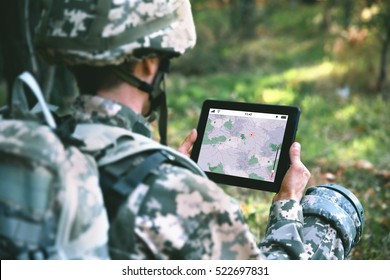 Soldier using map on tablet for orientation at forest - Powered by Shutterstock