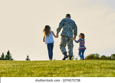 Soldier walking with little girls holding hands. Back view, father and daughters are walking together. - Powered by Shutterstock