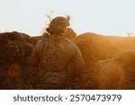 Soldier walks along a trench against the backdrop of sunset