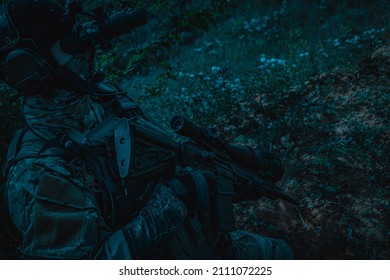 A Soldier With A Weapon In His Hands And A Night Vision Device. Armed Man At Night In The Forest.