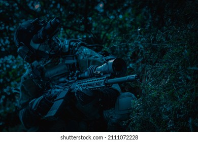 A Soldier With A Weapon In His Hands And A Night Vision Device. Armed Man At Night In The Forest.