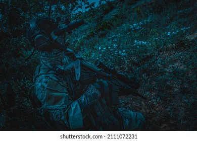 A Soldier With A Weapon In His Hands And A Night Vision Device. Armed Man At Night In The Forest.