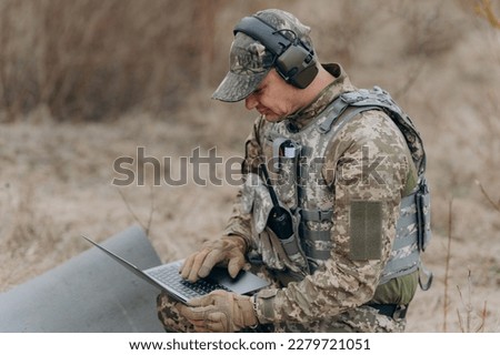 A soldier works on his laptop.