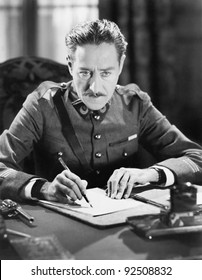 A Soldier Writing A Letter With A Gun Next To Him