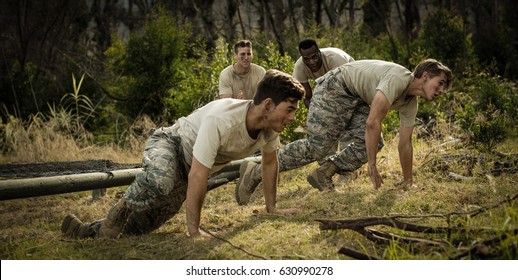 Soldiers crawling under the net during obstacle course in boot camp - Powered by Shutterstock