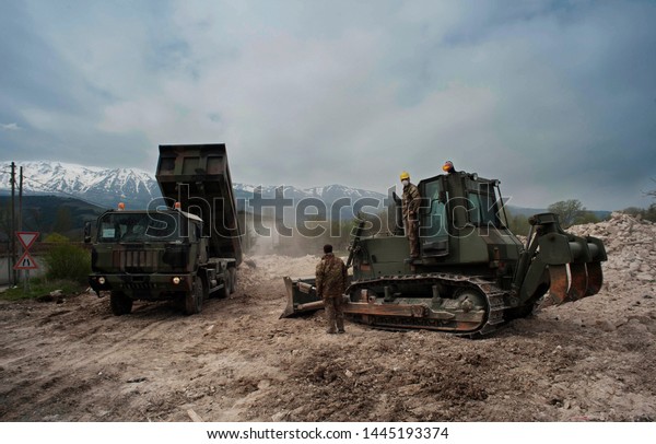 Soldiers  moving earth on a\
field