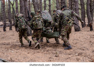 Soldiers Run Away From The Battlefield With Stretcher And Wounded Soldier