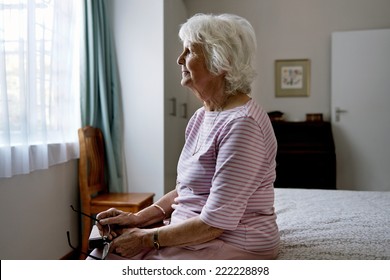 A solemn elderly woman sitting on her bed dealing with depression