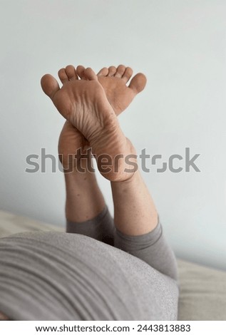 Soles and both bare feets of the young women lying at the bed