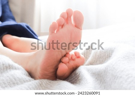 The soles of a woman's feet stretching her legs in bed