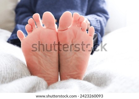 The soles of a woman's feet stretching her legs in bed