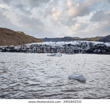 Solheimajokull picturesque glacier in southern Iceland. The tongue of this glacier slides from the volcano Katla. Beautiful glacial lake lagoon with blocks of ice and surrounding mountains.