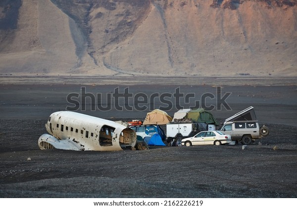 Solheimasandur, Iceland - Circa 2015: Remains of\
an old, crash-landed DC-3 aircraft with expedition camping vehicles\
parked around, exploring\
Iceland