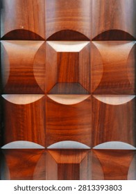 Solid 3d teak wood wall panel with repetitive concave convex square geometric carving shiny wood grain texture.