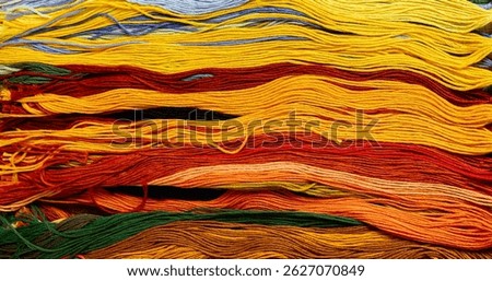 A solid background of colorful threads for cross stitch and needlework. Textured background for needlework and design. Rainbow of threads. Rows of colorful embroidery threads.