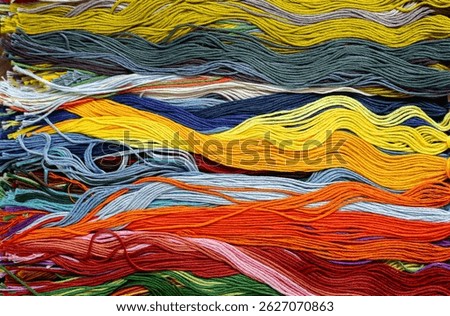 A solid background of colorful threads for cross stitch and needlework. Textured background for needlework and design. Rainbow of threads. Rows of colorful embroidery threads