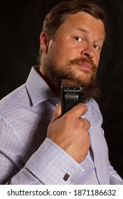 Solid Bearded Man Shaving By Electric Razor Studio Portrait On Black Background.