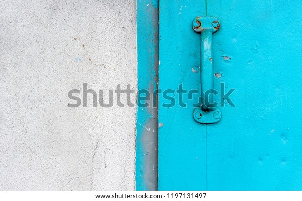 A solid blue door with\
metal handle takes up the right half of this split image while the\
concrete wall occupies the left half. Peeling paint enhances the\
weathered look.