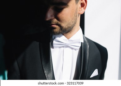 solid brunette groom in  black suit indoor sunlight