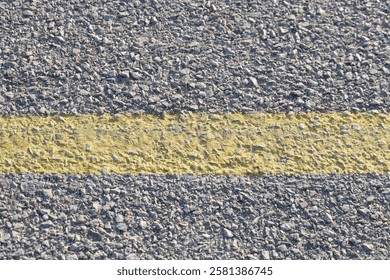 A solid, continuous yellow line on an asphalt road