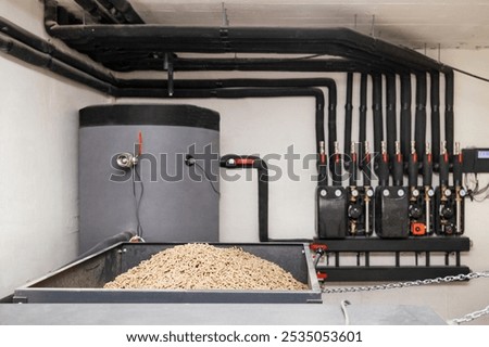 Solid Fuel Boiler with Automatic Pellets Burner and Buffer Tank with Hot Water, Pipes System, Pumps,Manometer in Boiler Room. Modern Eco Heater of Heating System with Wood Bio Pellets.
