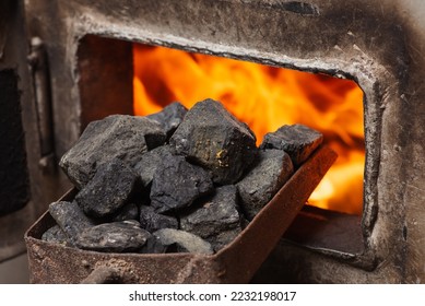 Solid fuel boiler with opened door and fire inside, scoop with coal nearby. Alternative ways of heating the house in cold winter season - Shutterstock ID 2232198017