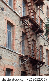 solid iron fire escape stairs on outside of old red brick building