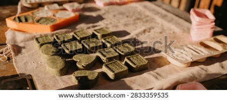 solid mint shampoo bars arranged on a cloth-covered worktable with mold trays visible, artisanal and natural.