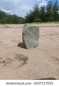 solid rock standing on the beach at sunny day