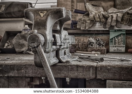 Solid tabletop vise on a messy workbench.