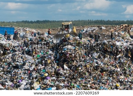 Solid waste disposal and landfill gas collection. Landfill with solid household waste. Dozer on Garbage dump with waste plastic and polyethylene. Environmental pollution. Soft focus.