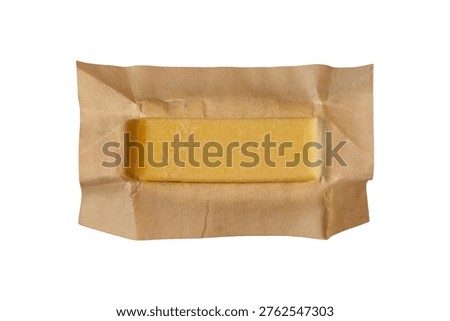 Solid yellow butter stick wrapped parchment paper isolated macro shot