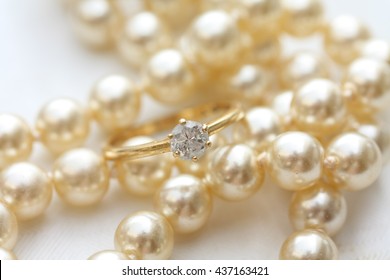 A Solitaire Diamond Engagement Ring On A Pearl Necklace