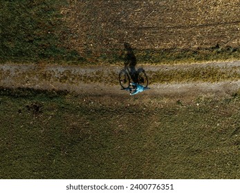 Solitary Cyclist: Aerial View of a Shadowy Ride - Powered by Shutterstock